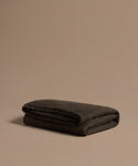 Folded chocolate alpaca throw on a beige background