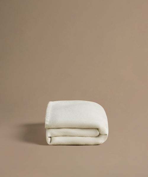 Folded beige blanket on a brown background