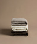 Stack of folded clothes in gray, white, and brown on a beige background