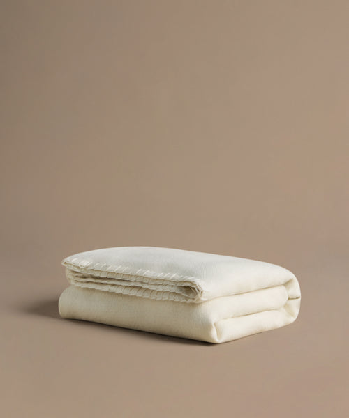 Folded beige blanket on a beige background