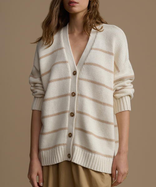 Woman wearing a cream and beige striped cardigan on a brown background