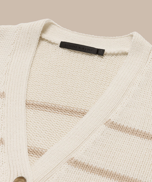 Close-up of the cream-colored Chloe Cardigan with subtle beige stripes, a v-neckline, and a black Jenni Kayne label on the collar—ideal for your spring and summer wardrobe.