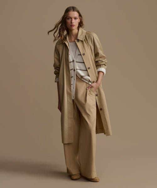 Woman wearing a beige trench coat on a brown background