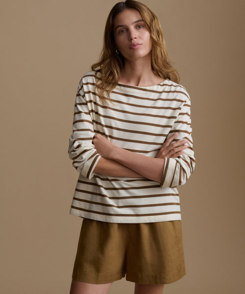 Woman wearing a striped shirt and shorts against a beige background