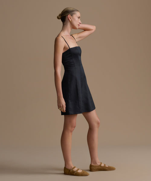 Woman wearing a black Coast Dress against a beige background