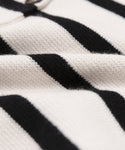 Close-up of the Cooper Cardigan, a soft knit with horizontal ivory and black stripes. The detailed texture showcases slight folds in the fabric, emphasizing its structured silhouette.