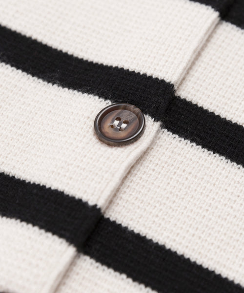 Close-up of the Cooper Cardigan’s knitted fabric, showing ivory black stripes and a brown button sewn onto one of the white stripes.