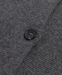Close-up of a black button sewn onto textured, dark grey knit fabric from the Cooper Cardigan. Buttonhole and stitch details are visible.