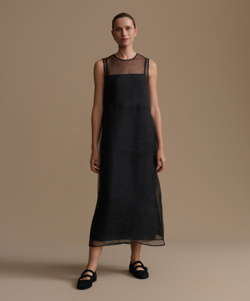 Woman wearing a black cora dress against a beige background