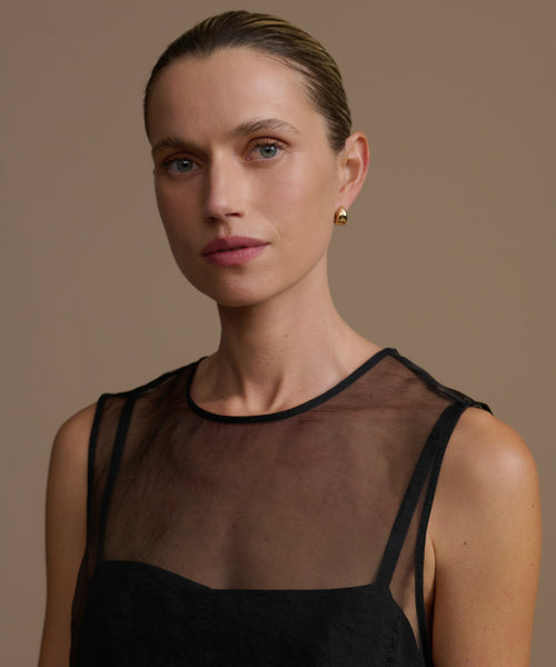 Woman wearing a black cora dress against a beige background