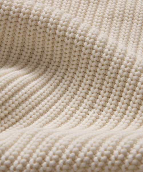 Close-up of the Cotton Cocoon Cardigan in ivory, crafted from organic cotton knit with a chunky textured pattern. Raised rows and gentle folds create soft shadows, highlighting the cozy details of this sustainable piece.