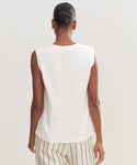 Seen from behind against a light background, a person with short dark hair in a bun wears the Easy Tank and cream pants with black vertical stripes. The Easy Tank offers 100% cotton comfort and effortless style.
