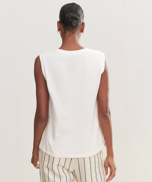 Seen from behind against a light background, a person with short dark hair in a bun wears the Easy Tank and cream pants with black vertical stripes. The Easy Tank offers 100% cotton comfort and effortless style.