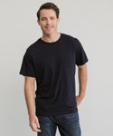 A man with short brown hair smiles at the camera, wearing the Mens Vintage Pocket Tee and blue jeans, standing against a light gray background.