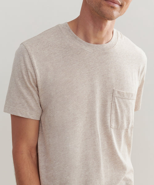 A person wearing the Mens Vintage Pocket Tee in light beige, featuring a chest pocket, shown from shoulders to mid-torso against a neutral background.
