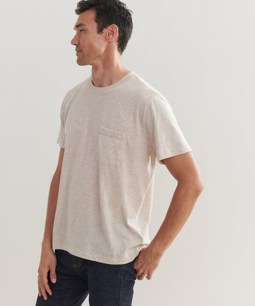 A man models the Mens Vintage Pocket Tee in light beige, made from 100% cotton. He stands against a plain background, turned slightly left with one hand in his jeans pocket.