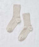 A pair of light beige Rib Socks, perfect for all seasons, is laid flat on a white fabric background with the toes facing opposite directions.