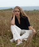 Woman sitting in a field with ocean view wearing a dark navy courtney top
