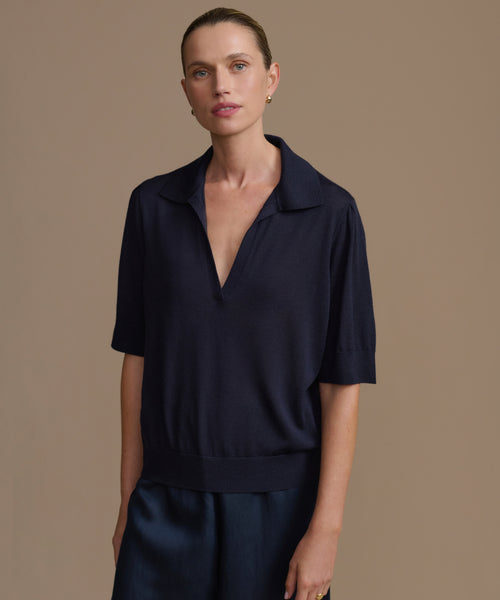 Woman wearing a dark navy courtney top against a brown background