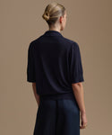 Woman wearing a navy courtney top and navy outfit against a beige background