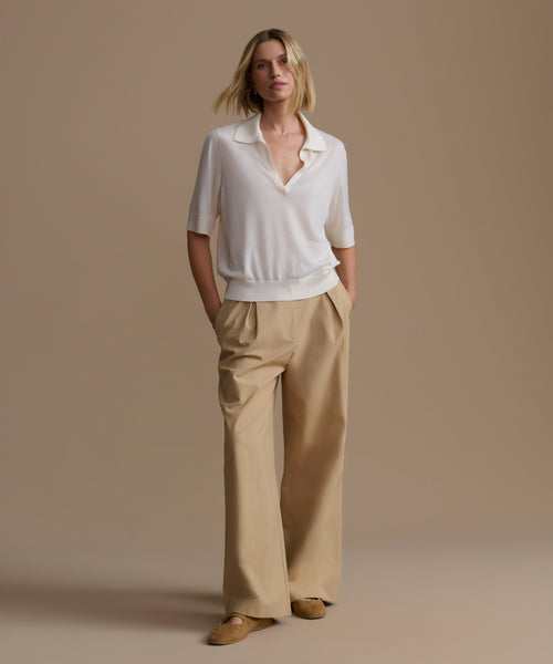 Woman wearing a ivory courtney top and beige pants against a beige background
