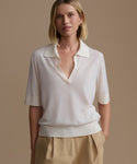 Woman wearing a ivory courtney top with a deep neckline against a beige background