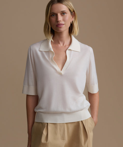 Woman wearing a ivory courtney top with a deep neckline against a beige background