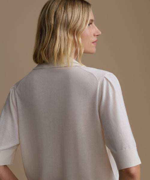 Woman wearing a ivory courtney top against a beige background
