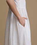White textured dress worn by a woman on a beige background