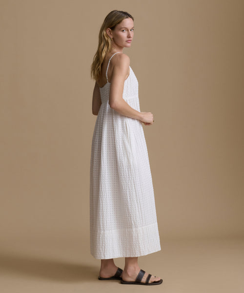 Woman wearing a white dress against a beige background
