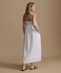 Woman wearing a white dress against a beige background