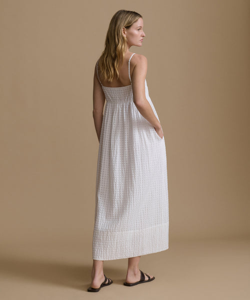 Woman wearing a white dress against a beige background