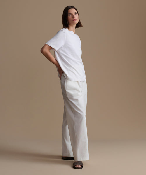 Woman wearing a white outfit against a beige background