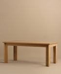 The Dining Table is a handmade rectangular piece crafted from solid white oak with four sturdy legs and is pictured against a plain beige background.