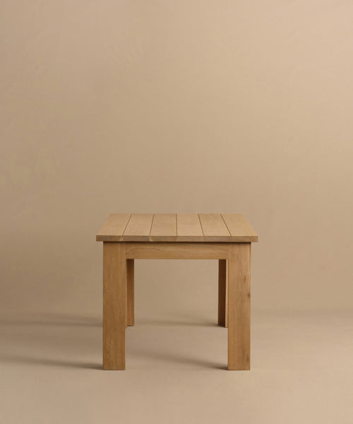 The Dining Table is a simple, handmade piece crafted from solid white oak, with a rectangular top and four straight legs. It is shown against a plain beige background.