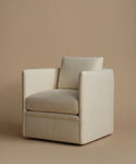 A modern square armchair upholstered in a warm cream-beige fabric, featuring a matching back cushion, set against a solid beige studio background.