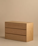 The Dune Dresser, a sleek and lightweight White Oak piece featuring three drawers, is pictured against a plain beige background.