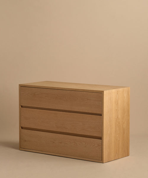 The Dune Dresser, a sleek and lightweight White Oak piece featuring three drawers, is pictured against a plain beige background.