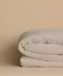 The Dusk Linen Duvet Cover, neatly folded, rests on a beige surface with a matching beige background.