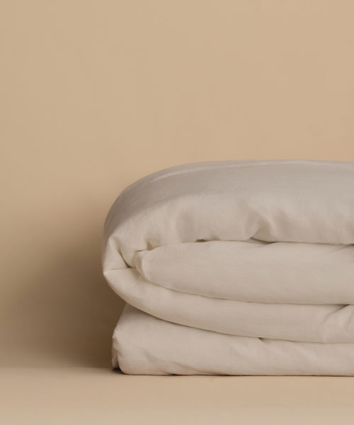 The Dusk Linen Duvet Cover, neatly folded, rests on a beige surface with a matching beige background.