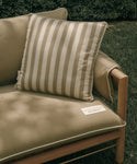 Beige cushion with striped pattern on a wooden chair outdoors