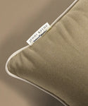 Close-up of a brown pillow with a Jenni Kayne label on a beige background
