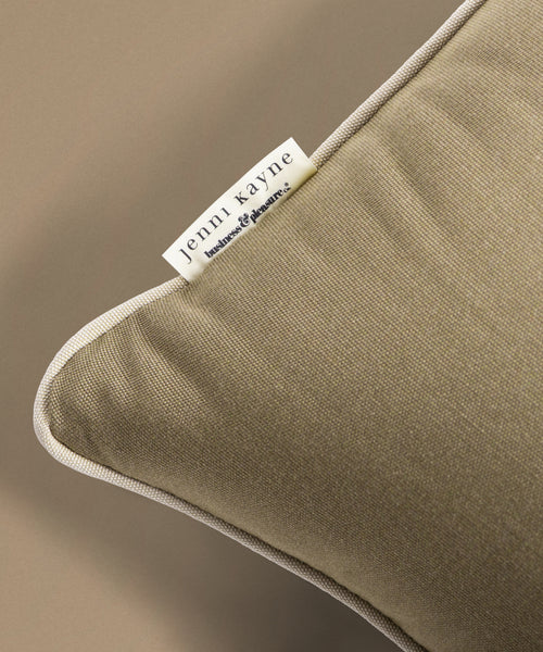 Close-up of a brown pillow with a Jenni Kayne label on a beige background