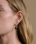 Close-up of a woman wearing a green bead earring with a beige background