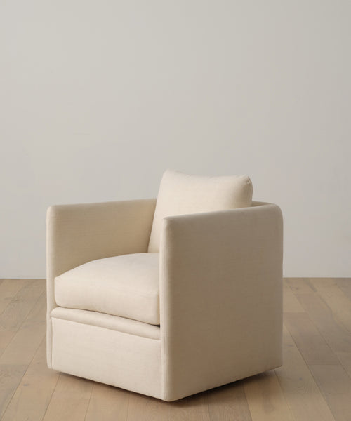 A modern, square cream-colored armchair with cushioned seat and backrest sits on a light wooden floor against an off-white wall, perfectly complementing the Fabric Swatch Beige Hemp.