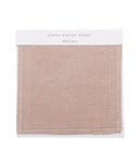 A Fabric Swatch Shell Linen shows a square piece of light pinkish-beige linen with stitched edges, attached to a white card—ideal for accenting the Cove Bed.