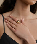 A woman in a black spaghetti strap top rests her hand on her chest, showcasing the Diamond Felix Dome Ring from Jenni Kayne Jewelry. The focus is on the sparkling ring and her neatly manicured nails.