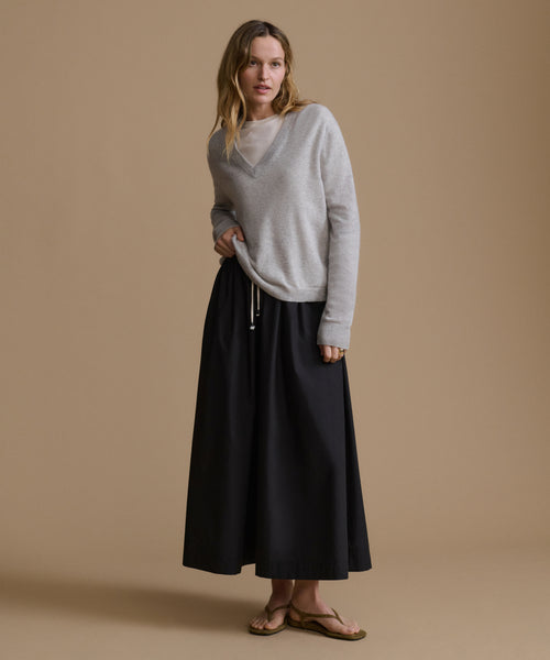 Woman wearing a gray sweater and black skirt on a beige background