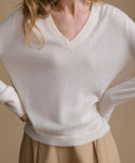 White sweater worn by a person on a beige background
