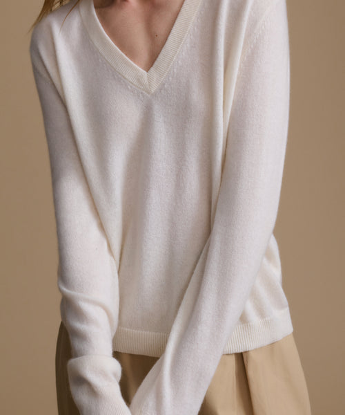 White sweater worn by a person on a beige background